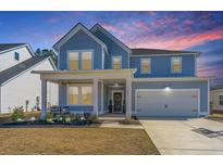 Charming two-story home showcasing a well-manicured front yard and an inviting covered porch at 143 Oyster Tide Ave, Summerville, SC 29485