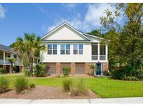 Inviting two-story home featuring well-manicured lawn, tall palm trees, and a lovely screened-in porch at 1717 Rivertowne Country Club Dr, Mount Pleasant, SC 29466