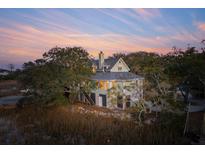 Two-story home with a chimney and lots of mature trees against a colorful sunset at 232 Haddrell St, Mount Pleasant, SC 29464