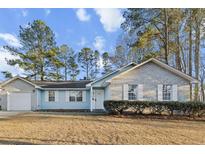 Charming single-story home with a well-manicured lawn, blue and brick exterior, and mature trees at 2929 Salamander Creek Ln, North Charleston, SC 29406