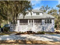 Two-story home featuring a large porch and landscaped front yard on a sunny day at 8834 Palmetto Rd, Edisto Island, SC 29438