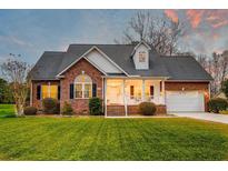 Charming brick home features a well-manicured lawn, inviting front porch, and attached two-car garage at 1006 Retreat Ave, Moncks Corner, SC 29461