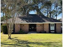 Charming brick home with well-manicured lawn, mature trees, and decorative details at 1025 Wellington Dr, Charleston, SC 29412