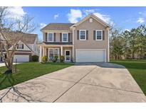 Charming two-story home with a well-manicured lawn and a large driveway on a sunny day at 315 Sabal Palmetto Ct, Moncks Corner, SC 29461