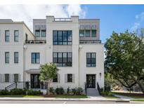 Three-story white brick home featuring black framed windows, a black metal roof deck, and professionally landscaped yard at 413 Spartina Ln, Charleston, SC 29492