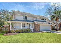 Charming two-story home featuring a welcoming front porch, a well-manicured lawn and an attached two-car garage at 764 Brown Dr, Charleston, SC 29412