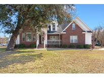 Charming brick home with a front porch and well-maintained lawn on a sunny day at 8696 Spring Chapel Ln, North Charleston, SC 29420