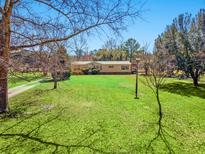 Well-maintained single-story home on a large, green lawn with mature trees under a clear, blue sky at 2285 Cooper Store Rd, Moncks Corner, SC 29461