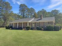 Charming brick home with a cozy front porch, mature trees, and a well-manicured lawn at 243 Country Club Blvd, Saint George, SC 29477