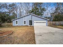 Charming blue home with an attached garage and driveway, surrounded by mature trees and an unfenced lawn at 4618 Moss Ct, Charleston, SC 29420
