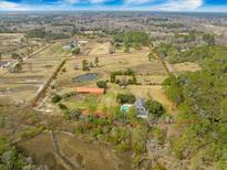 Expansive estate with private pond, pool, and outbuildings surrounded by lush landscaping and a secure red perimeter at 4801 Coon Club Rd, Meggett, SC 29449