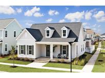 Charming single Gathering home featuring a cozy front porch, dormer windows, and manicured lawn at 509 Rhythm St, Summerville, SC 29486