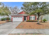 Charming red one-story home featuring a well-manicured lawn and attached two-car garage at 5408 Overland Trl, North Charleston, SC 29420