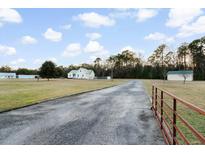 Lovely country home featuring a metal roof, long driveway, and spacious front yard at 5529 Golden Rice Ln, Ravenel, SC 29470