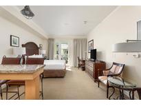 Comfortable bedroom features a king bed, work space, balcony access and neutral decor at 5804 Palmetto Dr # A-208, Isle of Palms, SC 29451