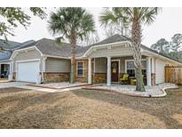 Inviting single story home featuring stone accents, manicured lawn, and a cozy covered front porch at 7034 Lanier St, Hanahan, SC 29410
