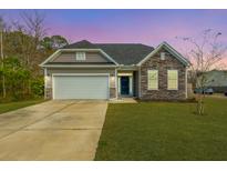 Charming single-Gathering home with stone accents, a two-car garage, and a well-manicured lawn at 108 Marinella Dr, Goose Creek, SC 29445