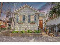 Charming single story home featuring blue shutters, window boxes, and landscaped front yard and concrete walkway at 312 President St, Charleston, SC 29403