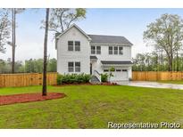 Charming two-story home with an attached two car garage, green lawn and a wood fence at 1020 Drakeford St # 9P, Saint George, SC 29477