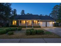 Charming brick home at twilight featuring an inviting front porch and attached two-car garage at 103 Night Hawk Ln, Summerville, SC 29485