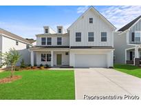 Charming two-story white farmhouse with a well-manicured lawn and a two-car garage at 1047 House Finch Ave # Cc3-19-2P, Ravenel, SC 29470