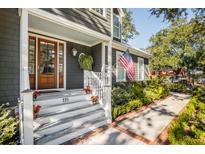 Charming front porch with wooden door, stairs adorned with flowers, and American flag creating a welcoming entrance at 118 Freeman St, Mount Pleasant, SC 29464