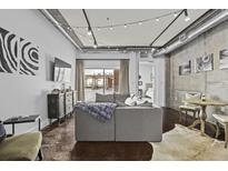 Modern living room featuring exposed ductwork, string lights, a gray sofa, and an open patio at 150 Bee St # 312, Charleston, SC 29401