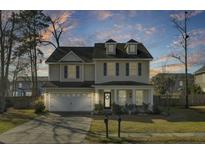 Charming two-story home boasts a welcoming front porch and well-maintained landscaping at sunset at 314 Foxbank Plantation Blvd, Moncks Corner, SC 29461