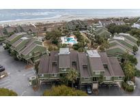 Aerial view of green condo complex near beach with palm trees, parking, and a pool on a sunny day at 7000 Palmetto Dr # 5A, Isle of Palms, SC 29451