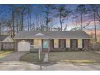 Charming brick home with an attached garage, a well-maintained lawn and a bright blue front door at 105 Alan Ct, Summerville, SC 29485