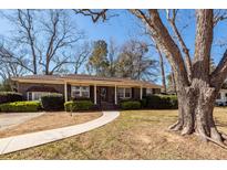 Charming brick home featuring a well-manicured lawn, mature tree, and inviting walkway to the front door at 1452 Glencoe Dr, Mount Pleasant, SC 29464