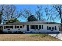 Charming single-story home with white brick, black shutters, flower boxes and an American flag flying by the front door at 2137 Barbour Dr, Charleston, SC 29414