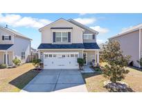 Charming two-story home featuring a two car garage, welcoming front porch, and well-manicured landscaping at 267 Cameron St, Summerville, SC 29486