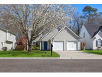 Charming two-story home with a blue door, two-car garage, and a beautiful flowering tree in the front yard at 350 Arlington Dr, Charleston, SC 29414