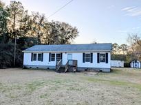 Charming single-story home featuring white siding, black shutters, and a well-maintained front yard at 5181 Dr Taylor Rd, Adams Run, SC 29426