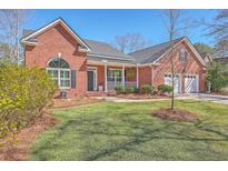 Beautiful brick home with a well-manicured lawn, inviting front porch, and a two-car garage at 8757 E Fairway Woods Dr, North Charleston, SC 29420