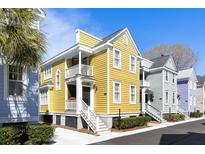 Charming yellow two-story home with double balconies and manicured landscaping, set under a clear blue sky at 108 Smith St # 108-C, Charleston, SC 29403