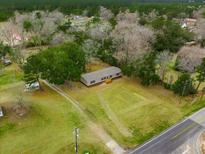 An aerial view of a single-story house with a large yard and surrounding trees and foliage at 1399 Old Whitesville Rd, Moncks Corner, SC 29461