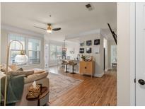Cozy living room features hardwood floors, a ceiling fan, and large windows for natural light and a view to the dining area at 1821 Chatelain Way # 1821, Mount Pleasant, SC 29464