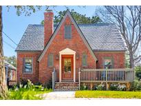 Charming brick Tudor-style home featuring a quaint front porch and meticulously maintained landscaping at 285 Grove St, Charleston, SC 29403