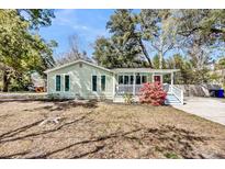 Charming single-story home with front porch and a red door, surrounded by mature trees at 3020 Marlin Rd, Johns Island, SC 29455