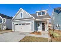 Charming home with a white garage door, blue siding, and a well-maintained front yard on a clear day at 417 Grove End Rd, Moncks Corner, SC 29461