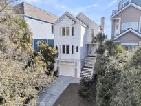 Beautiful white home with a garage and stairs leading to the front door surrounded by lush landscaping at 45 Ocean Point Dr, Isle of Palms, SC 29451