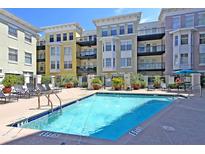 Community pool with lounge chairs, palm trees, and colorful condos surrounding the relaxation area at 498 Albemarle Rd # 306, Charleston, SC 29407