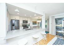 Bright kitchen featuring white cabinets, stainless appliances, stone countertops, and seating at the counter at 5541 Green Dolphin Way, Kiawah Island, SC 29455
