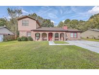 Charming brick home with an arched porch, benches, green lawn and a brick chimney at 7791 Peppercorn Ln, North Charleston, SC 29420