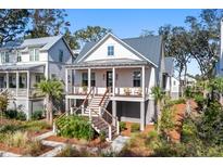 Charming two-story home boasts a welcoming porch, a metal roof, and manicured landscaping for curb appeal at 8067 Jack Island Dr, Johns Island, SC 29455