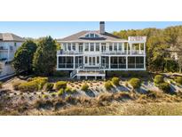 Expansive two-story coastal home with multiple balconies and screened-in porches overlooking the manicured dunes at 1136 Ocean Forest Ln, Seabrook Island, SC 29455
