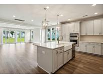 Bright open kitchen features white cabinets, stainless appliances, farmhouse sink, and hardwood floors at 210 Quimby Hill Dr, Huger, SC 29450