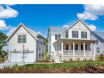 Charming white two-story home with a two-car garage and inviting front porch on a sunny day at 3019 Eventide Dr, Johns Island, SC 29455